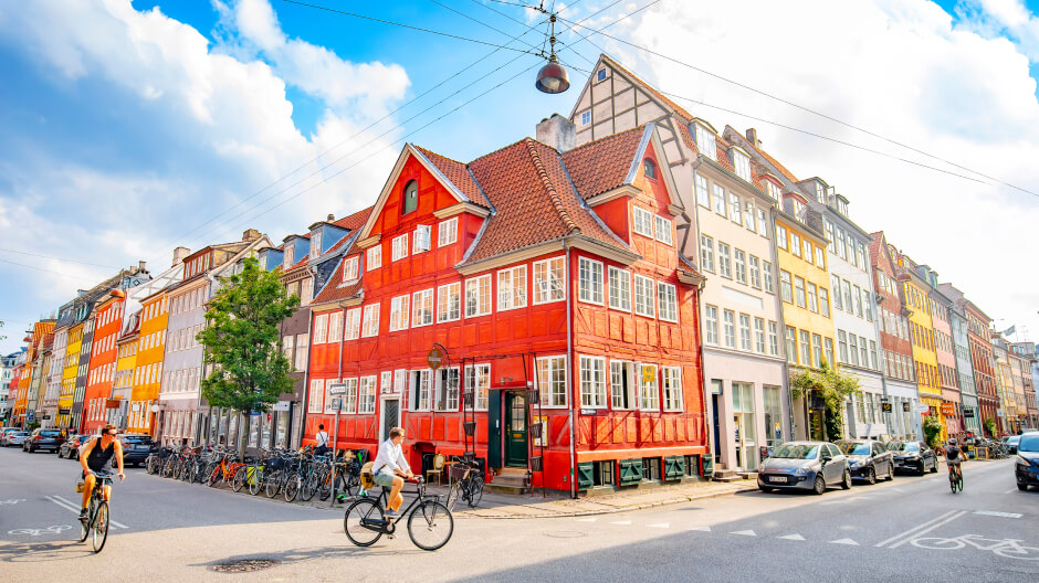 Joyful citizens riding bikes against a background of colorful buildings in Copenhagen