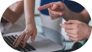 Two people discussing something on a laptop, with one pointing at the screen and the other hand hovering over it